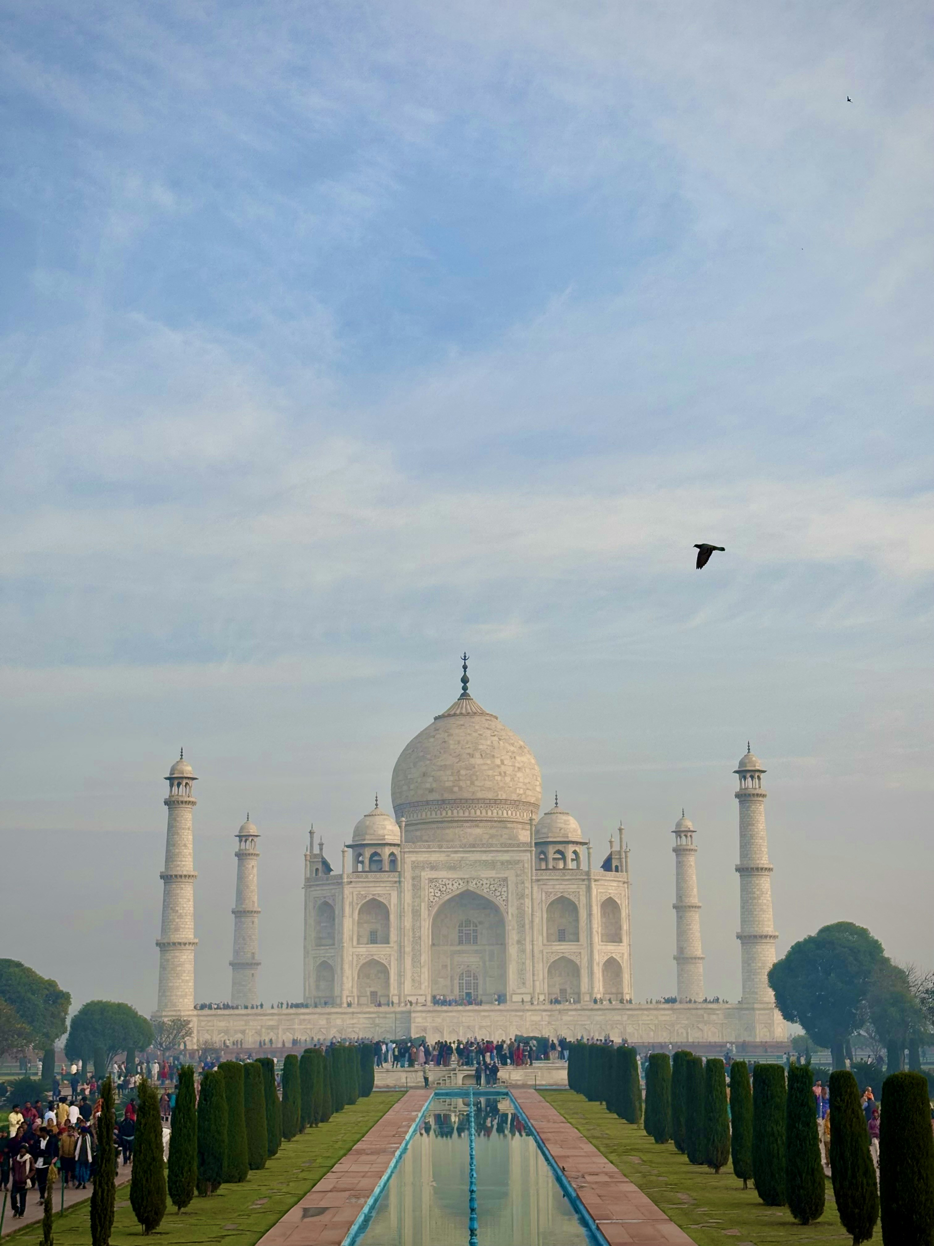 A large white building with a long pool in front of it