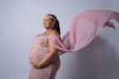 A pregnant woman in a pink gown holding a pink shawl