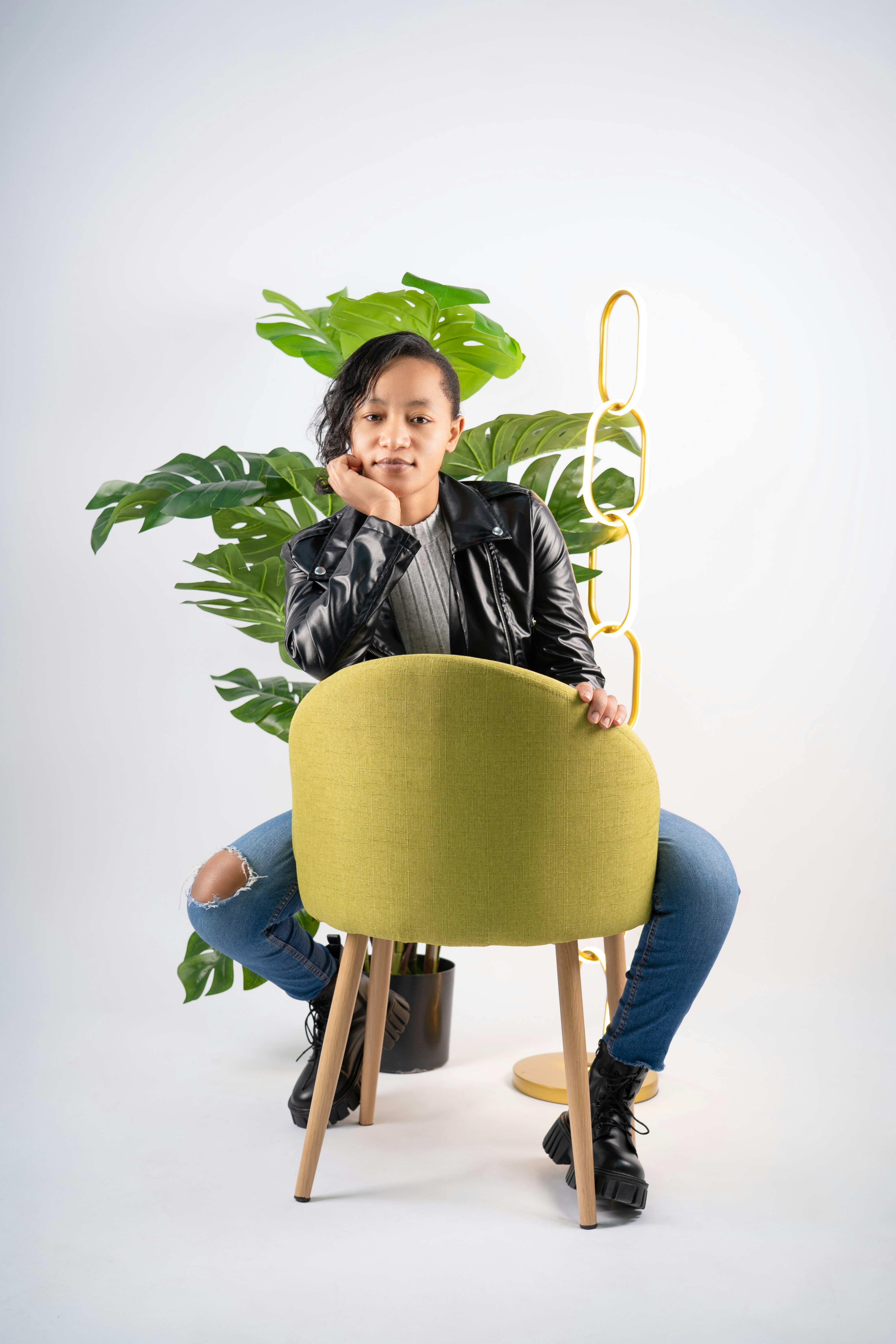 A woman sitting on a chair with a plant in the background