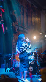 A woman standing on a stage singing into a microphone