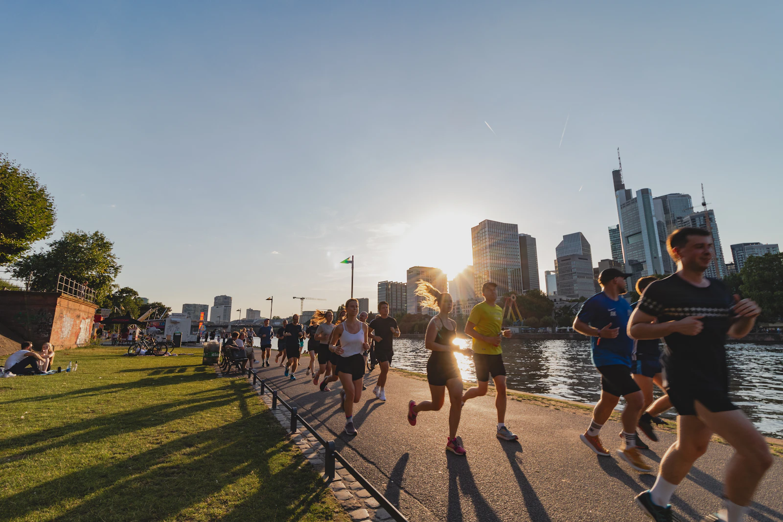 Grupo de corrida trotando à beira do rio no fim da tarde