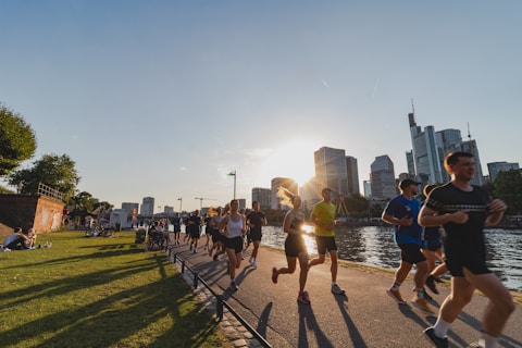 Grupp löpare springer längs floden i solnedgång