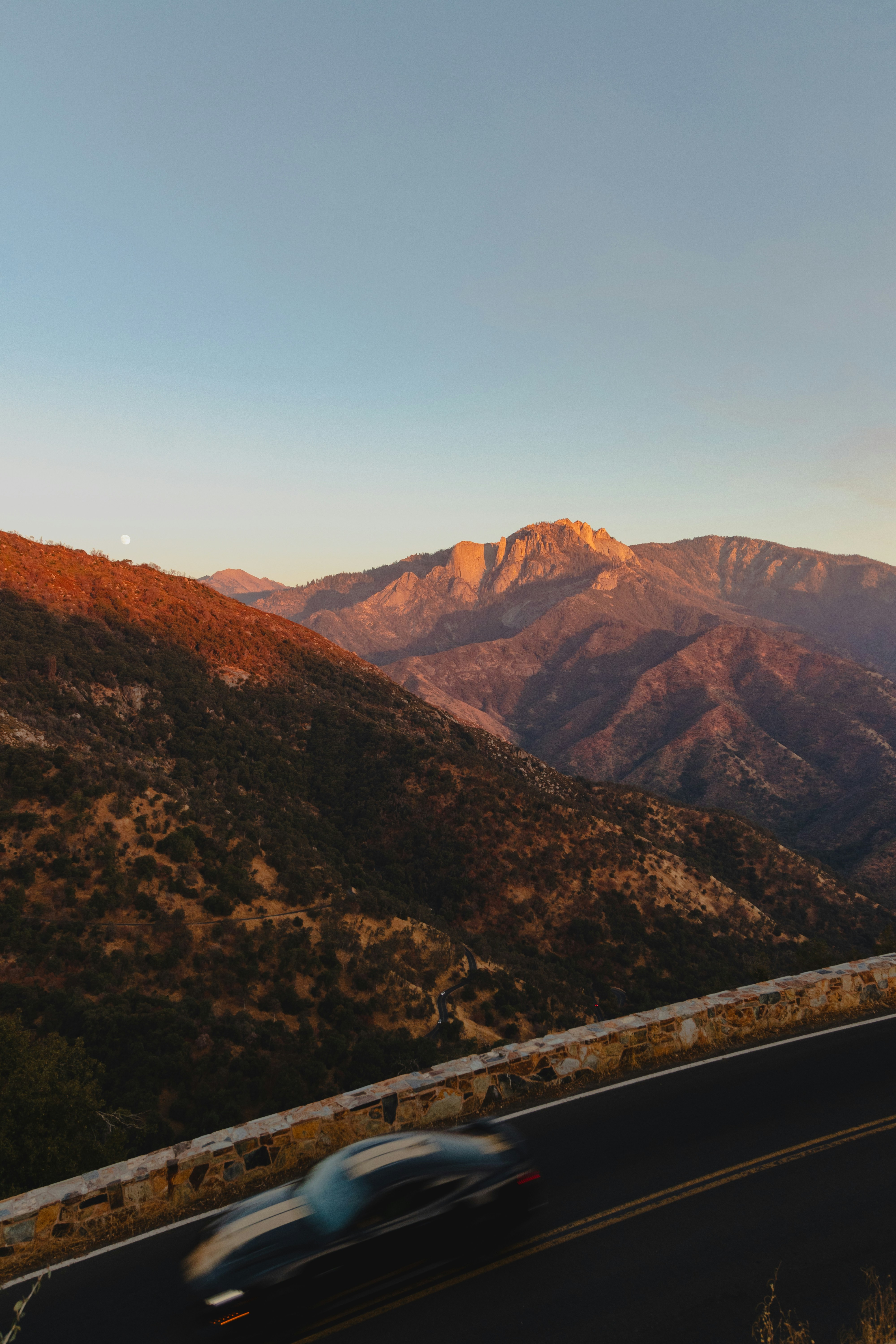 A car driving down a road with mountains in the background
