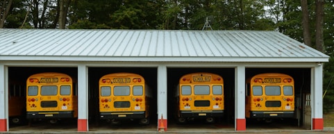 A row of yellow school buses parked in front of a building