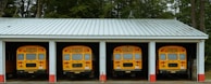 A row of yellow school buses parked in front of a building