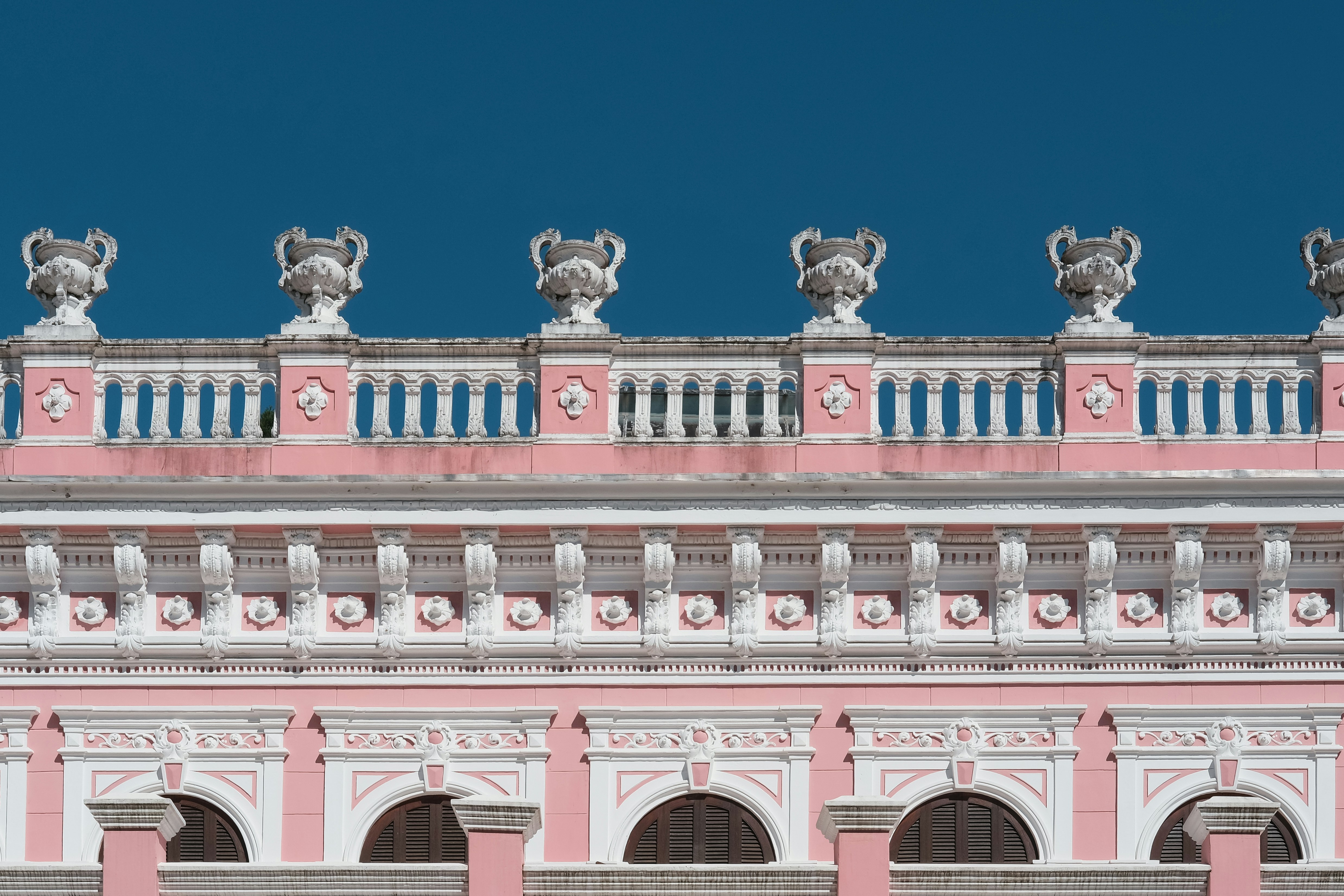 A pink and white building with statues on top of it