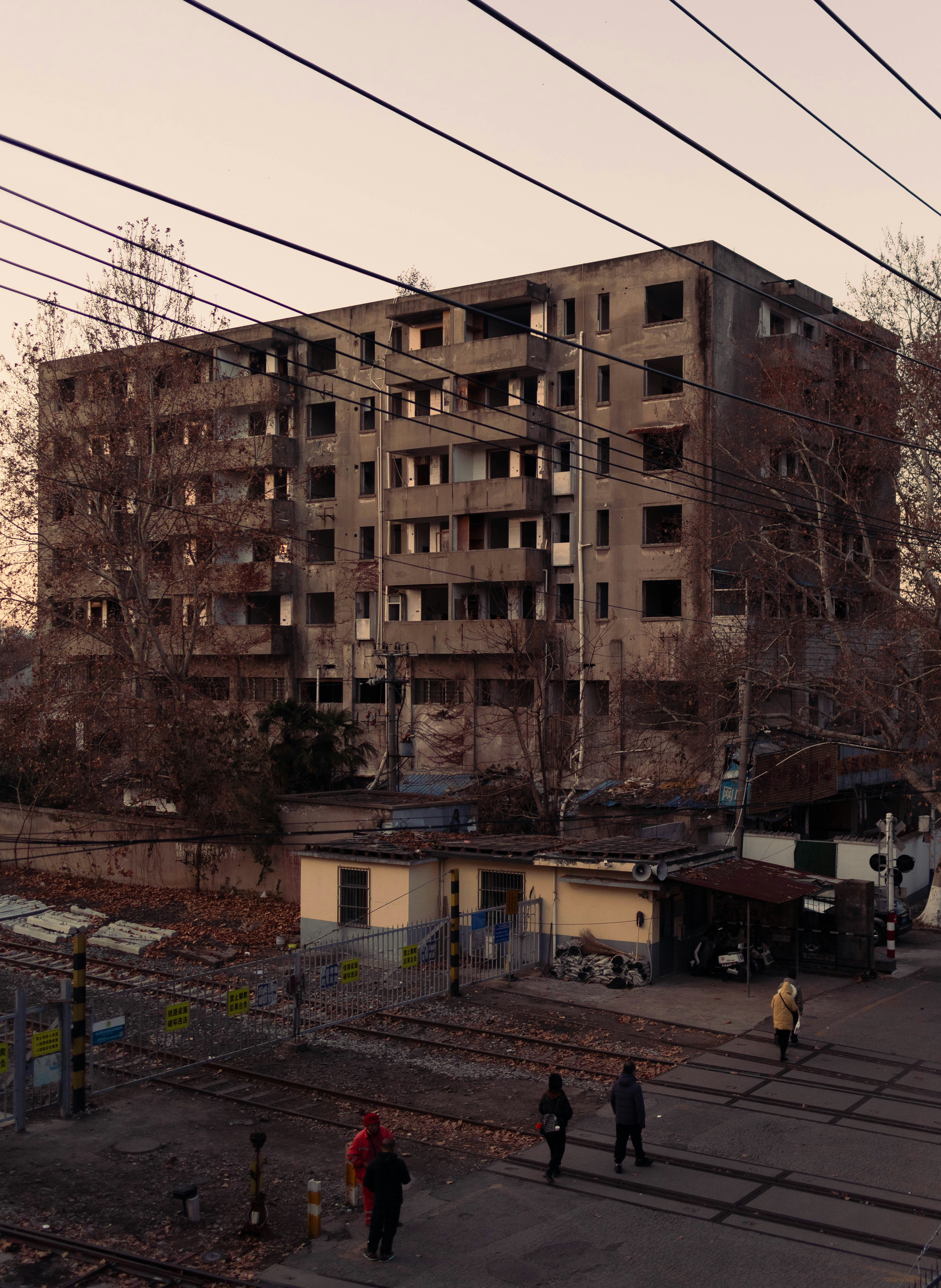 A group of people walking down a street next to a tall building