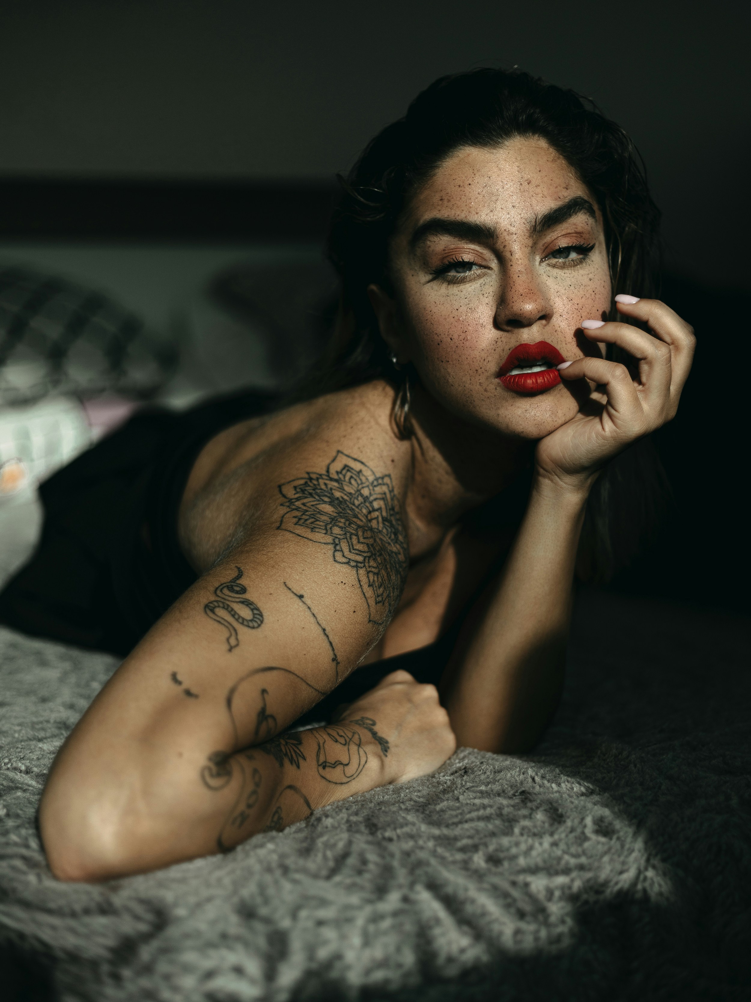 A woman with tattoos laying on a bed