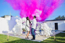 A man and a woman standing in front of a building with colored powder