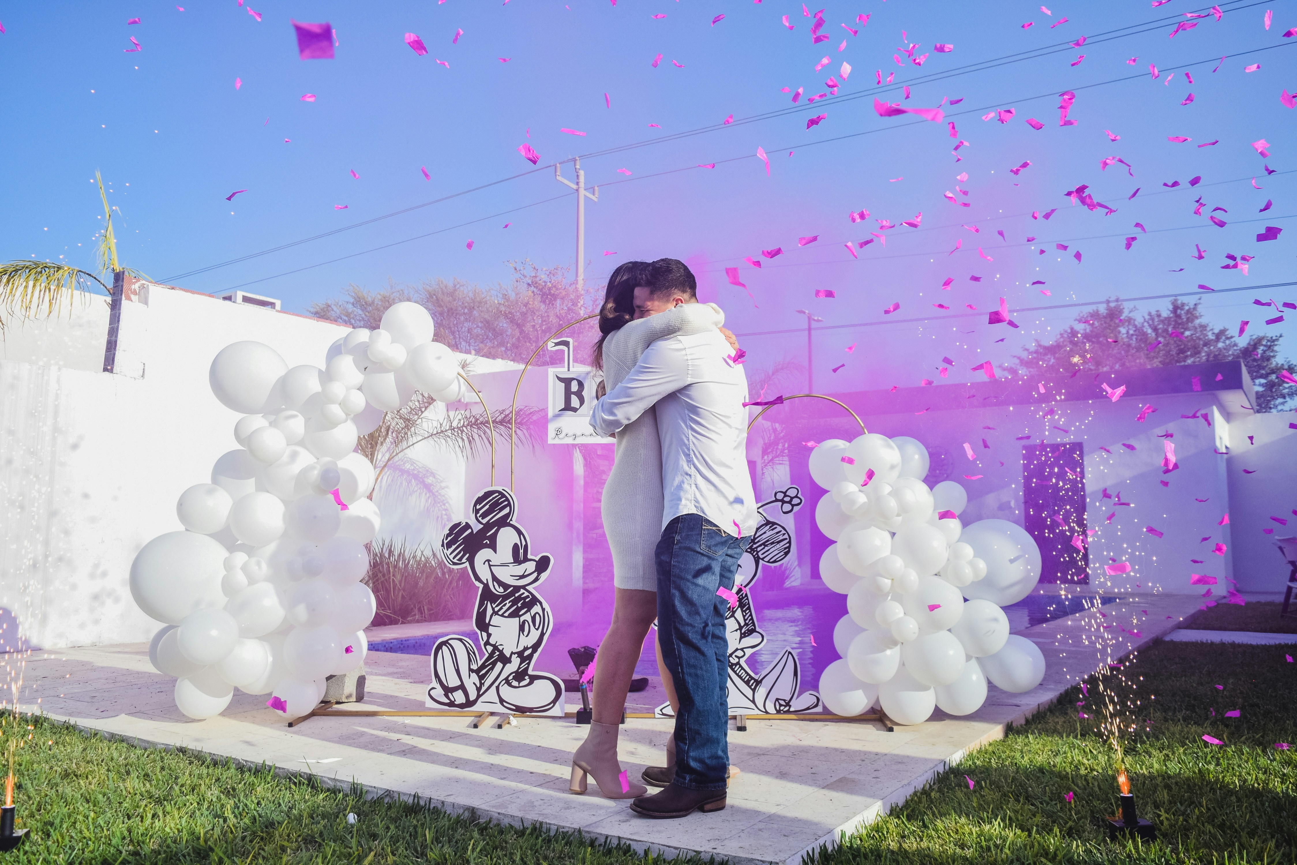 A man and a woman kissing in front of balloons