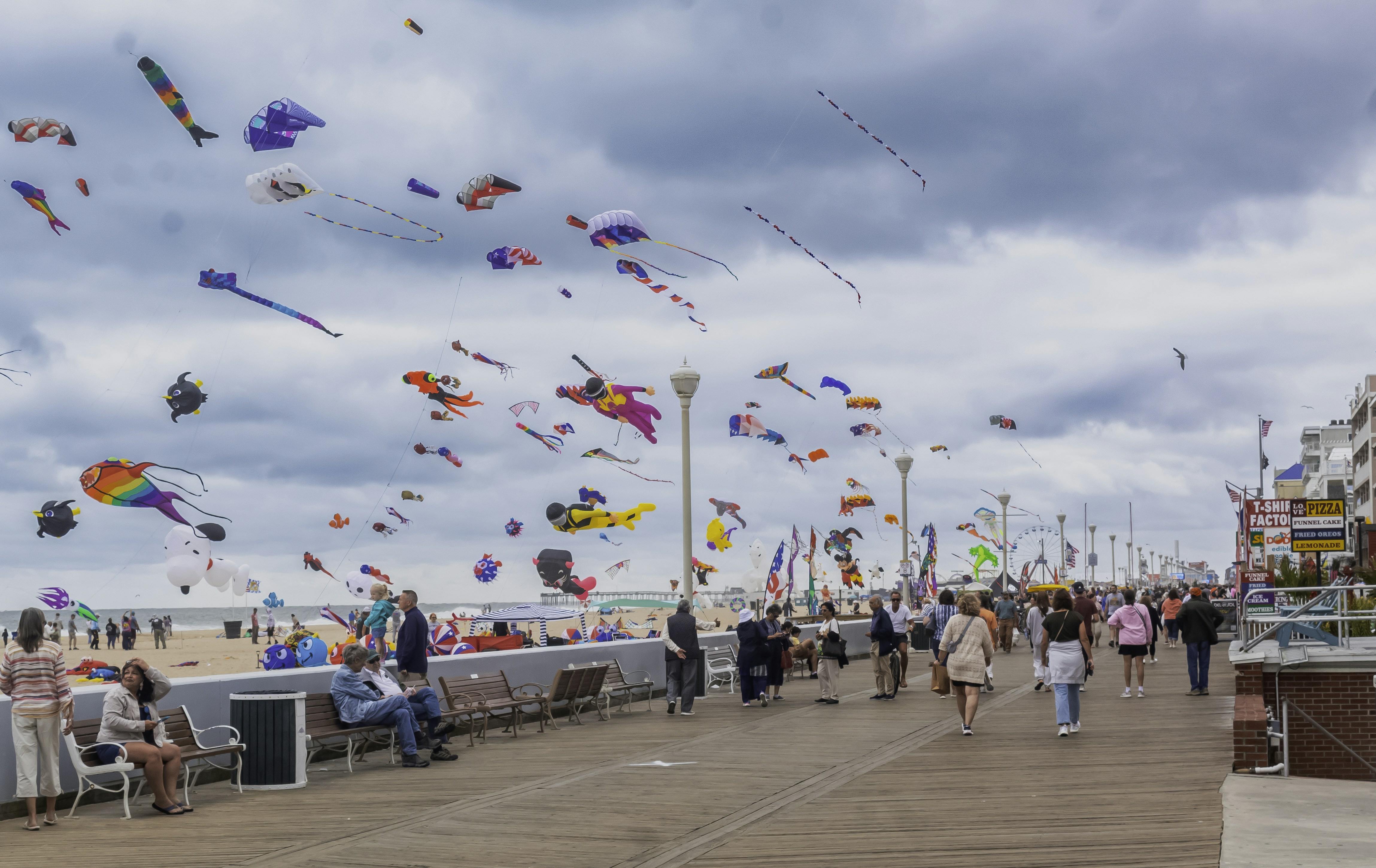 A crowd of people flying kites on top of a sandy beach