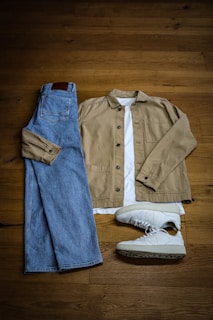 A pair of jeans, a jacket, and a pair of sneakers are laid out
