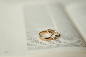 Two gold wedding rings sitting on top of an open book