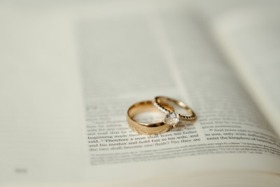 Two gold wedding rings sitting on top of an open book