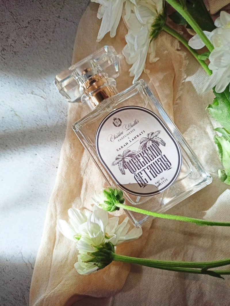 Sticlă de parfum lângă flori albe