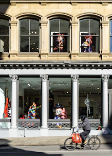 A man riding a bike down a street past a tall building
