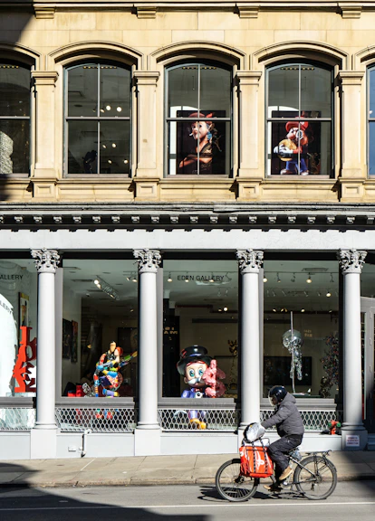 A man riding a bike down a street past a tall building