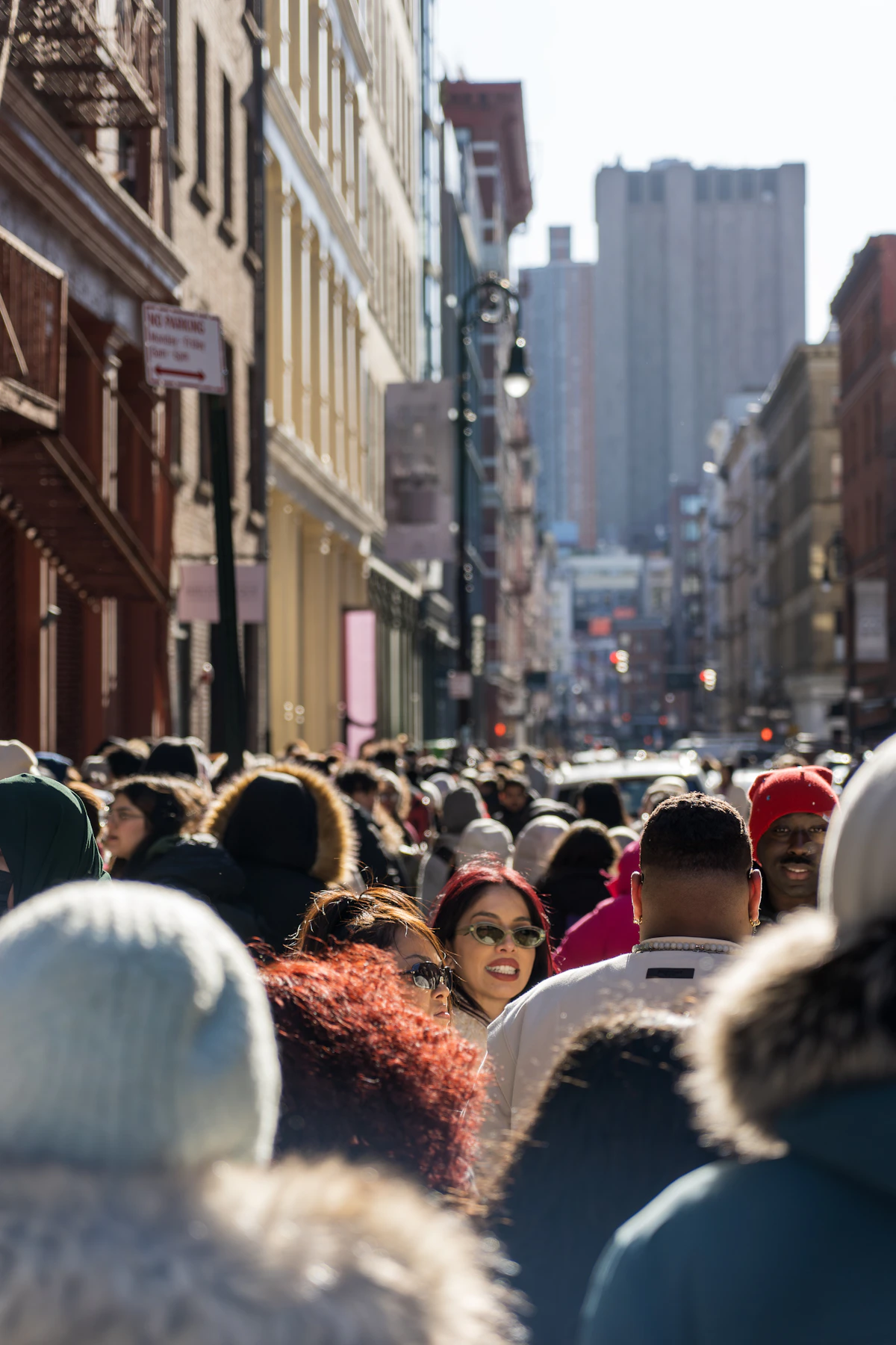 A crowd of people walking through a sunlit street in SoHo, Manhattan