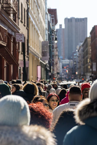A crowd of people walking down a street next to tall buildings