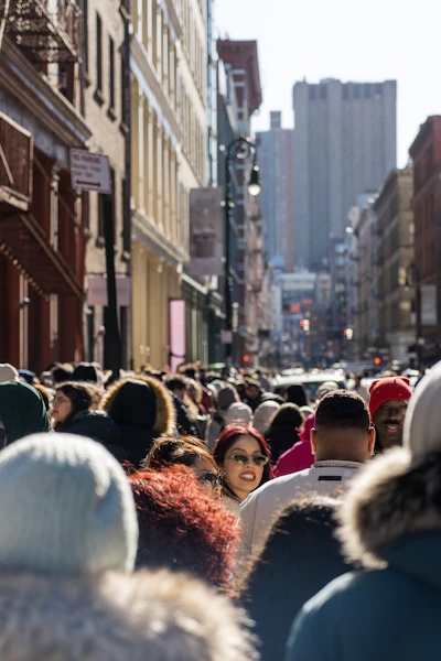 A crowd of people walking down a street next to tall buildings