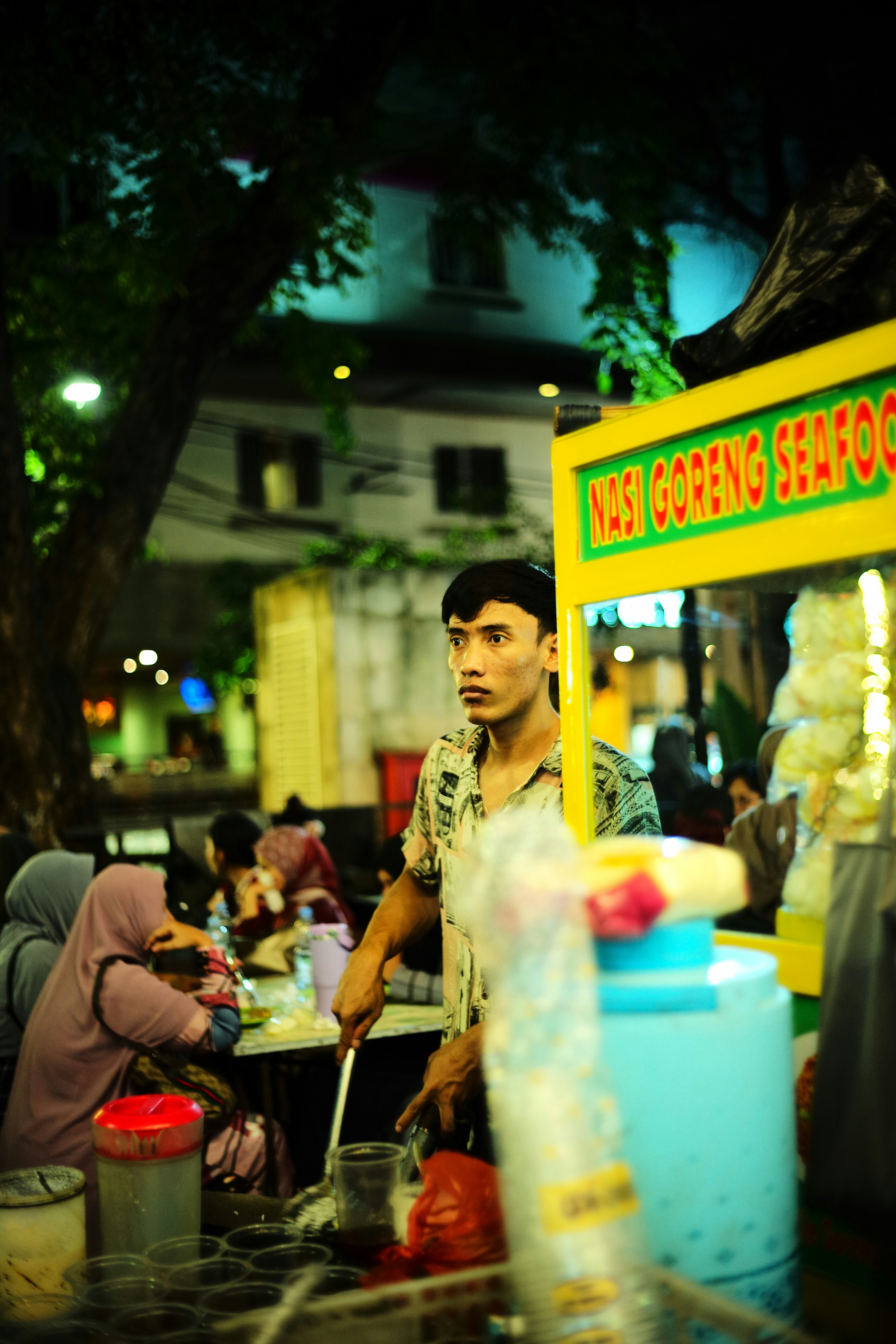 Seorang pria berdiri di depan kios makanan