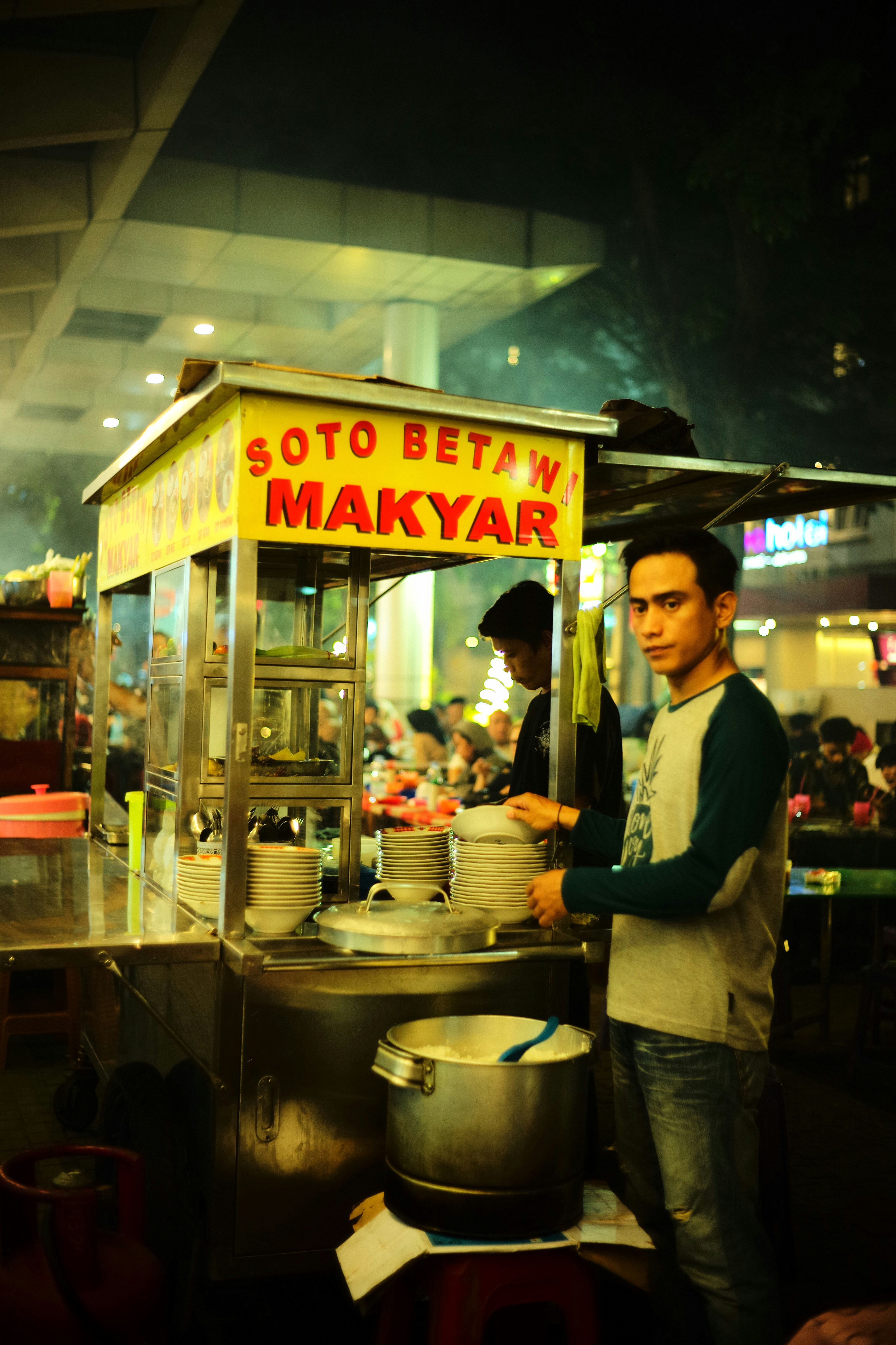 Seorang pria berdiri di depan gerobak makanan