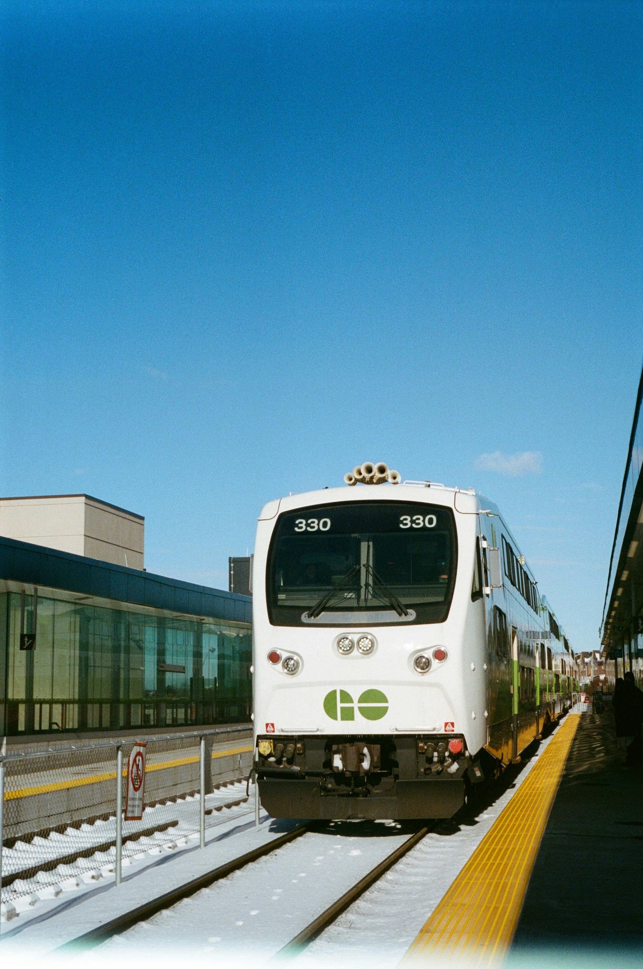 A white train traveling down train tracks next to a building