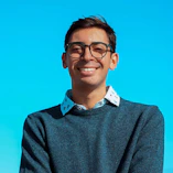 A man wearing glasses standing in front of a blue sky