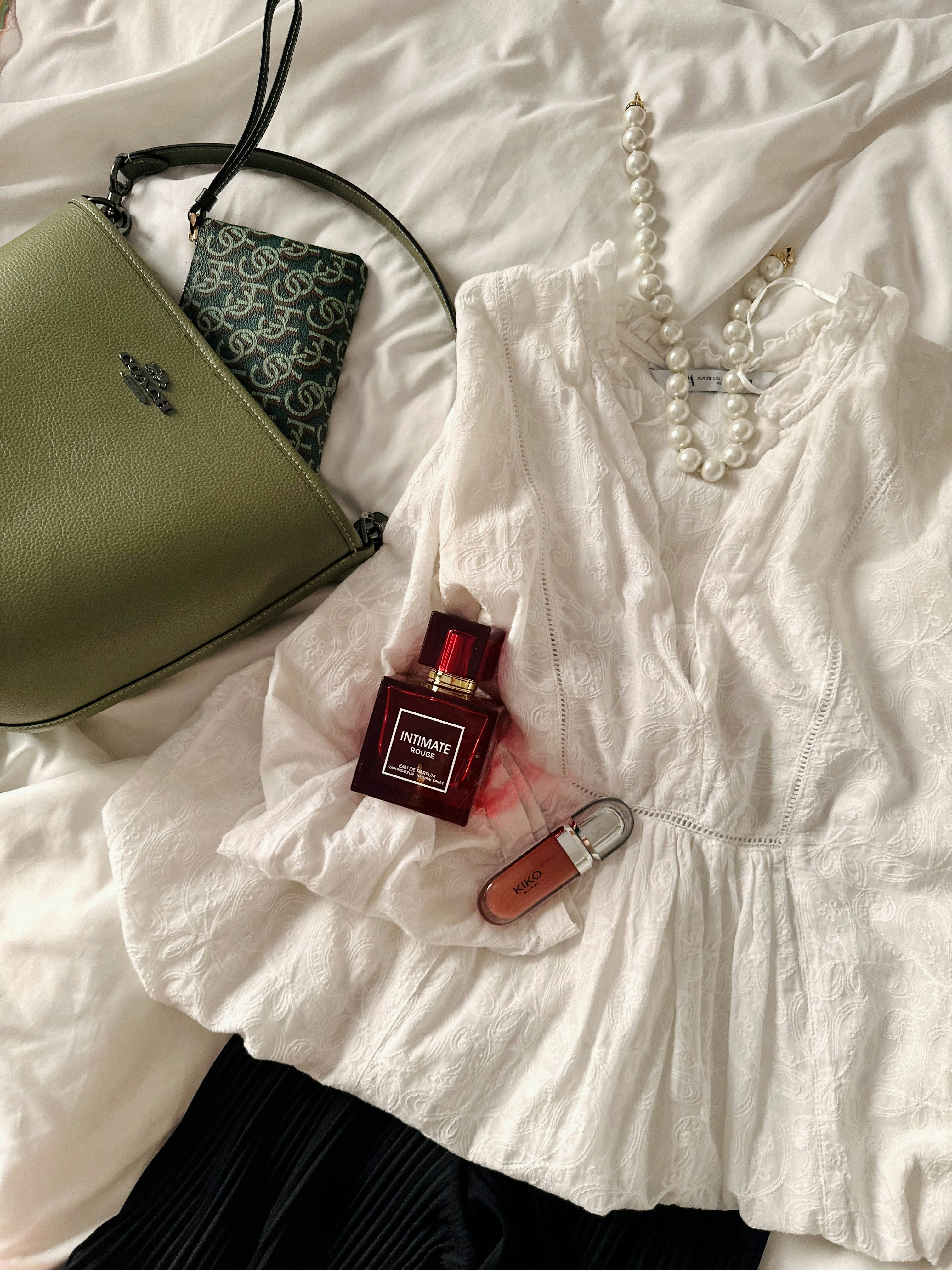 A white shirt and a green purse on a bed