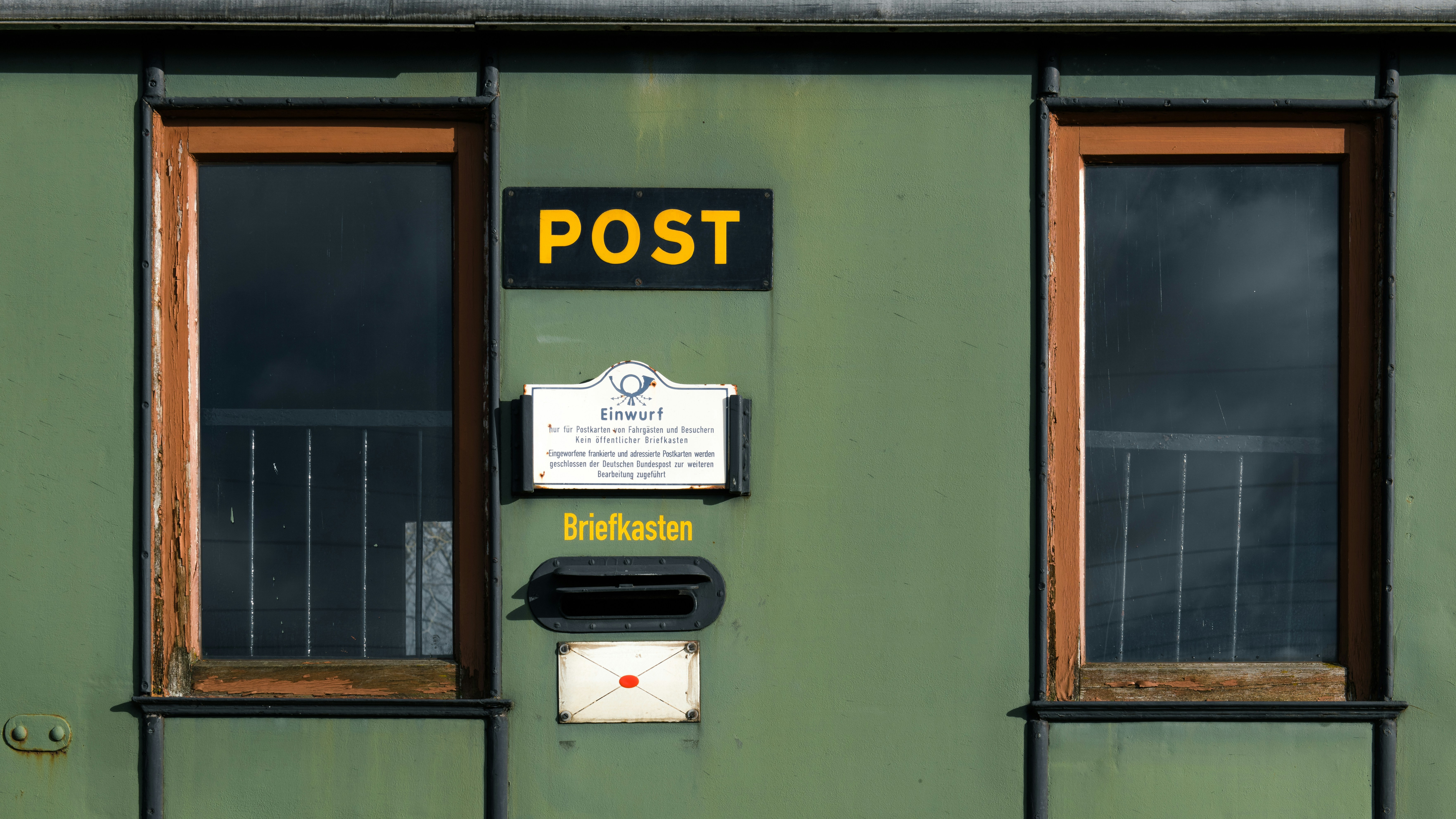 A green building with two windows and a sign on it