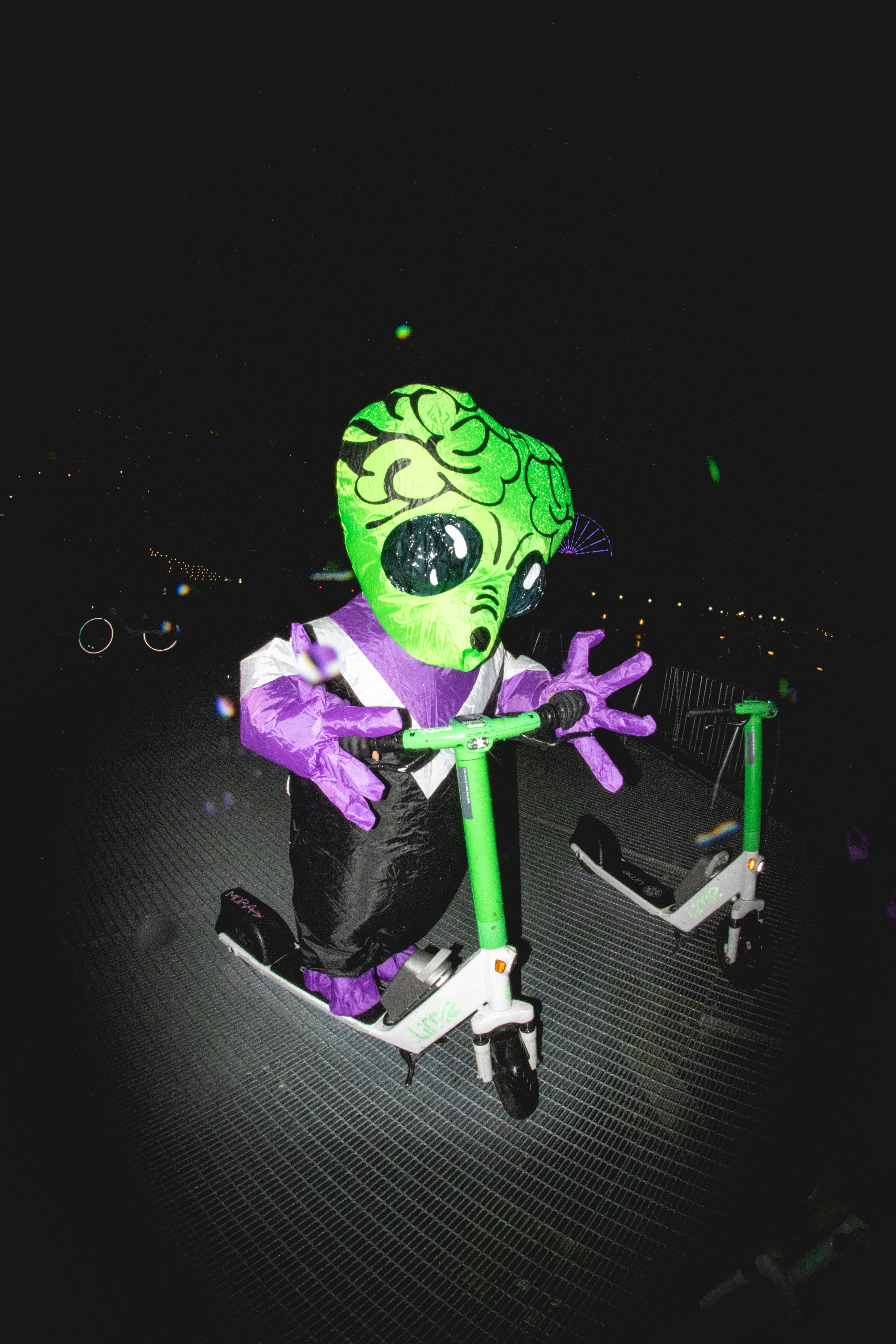 A green and purple monster riding a scooter
