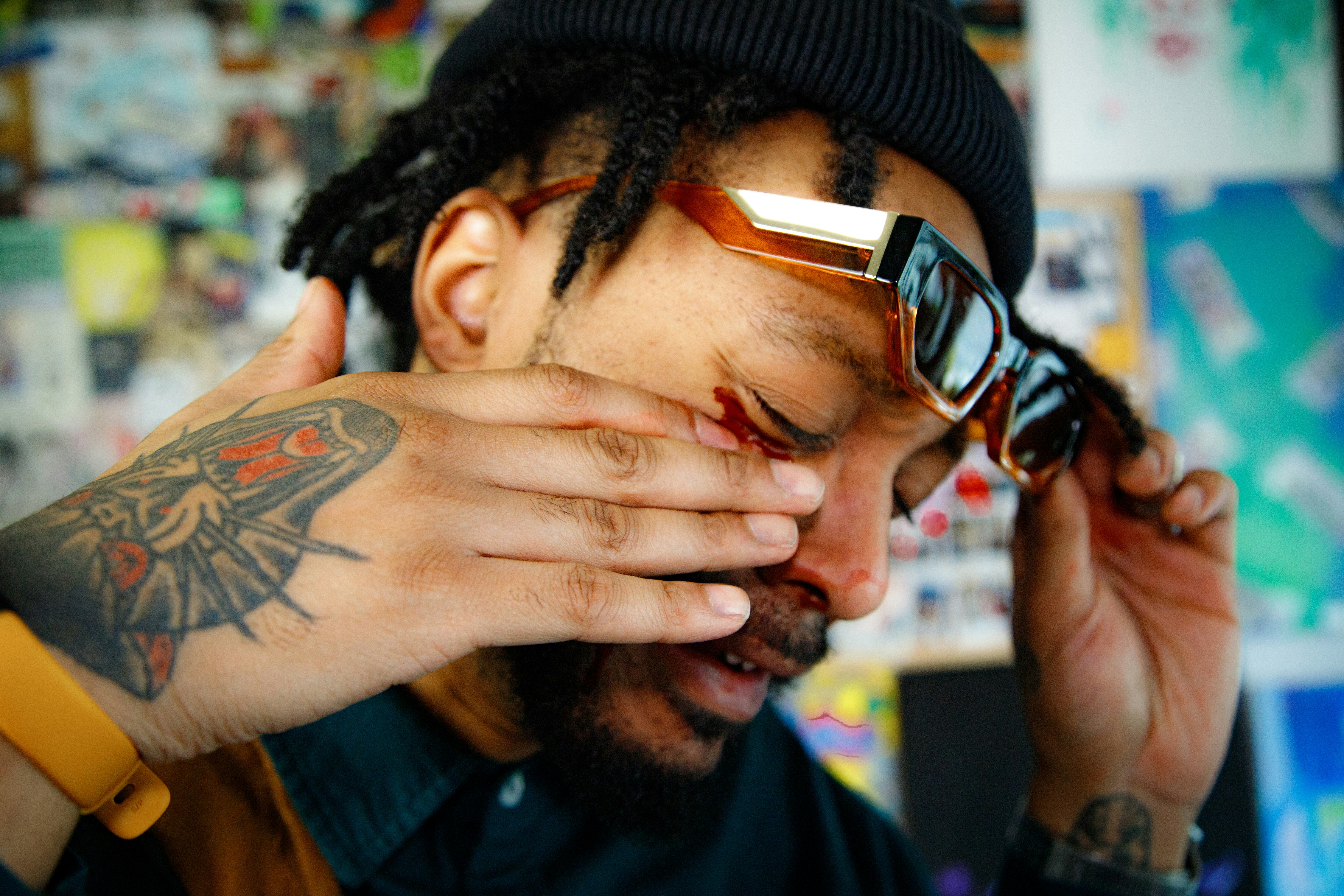 A man with a tattoo on his arm covering his eyes