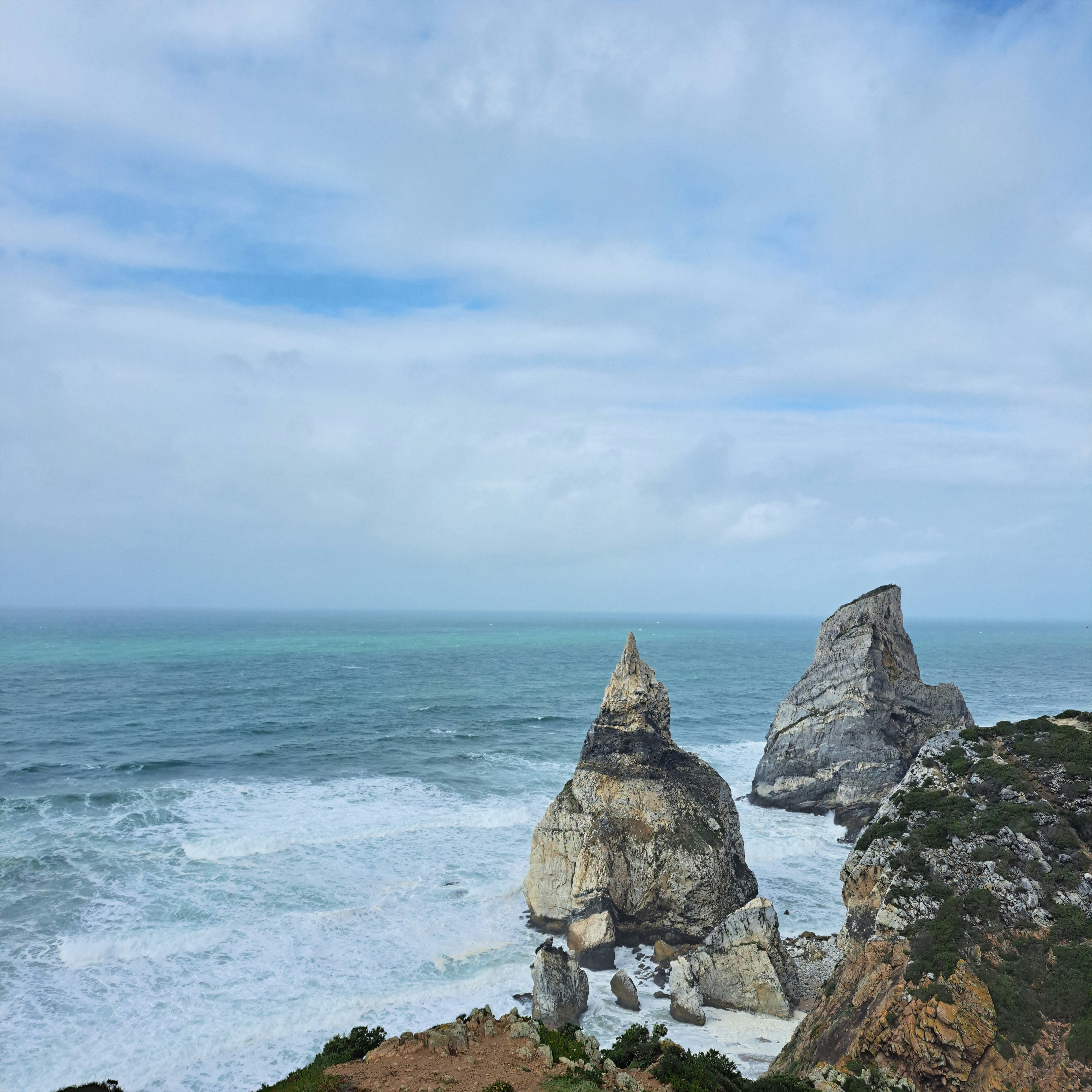 A couple of rocks sitting on top of a cliff near the ocean