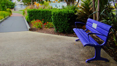 A blue bench sitting on the side of a road