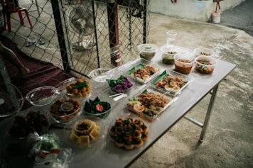 A table topped with lots of food next to a fence