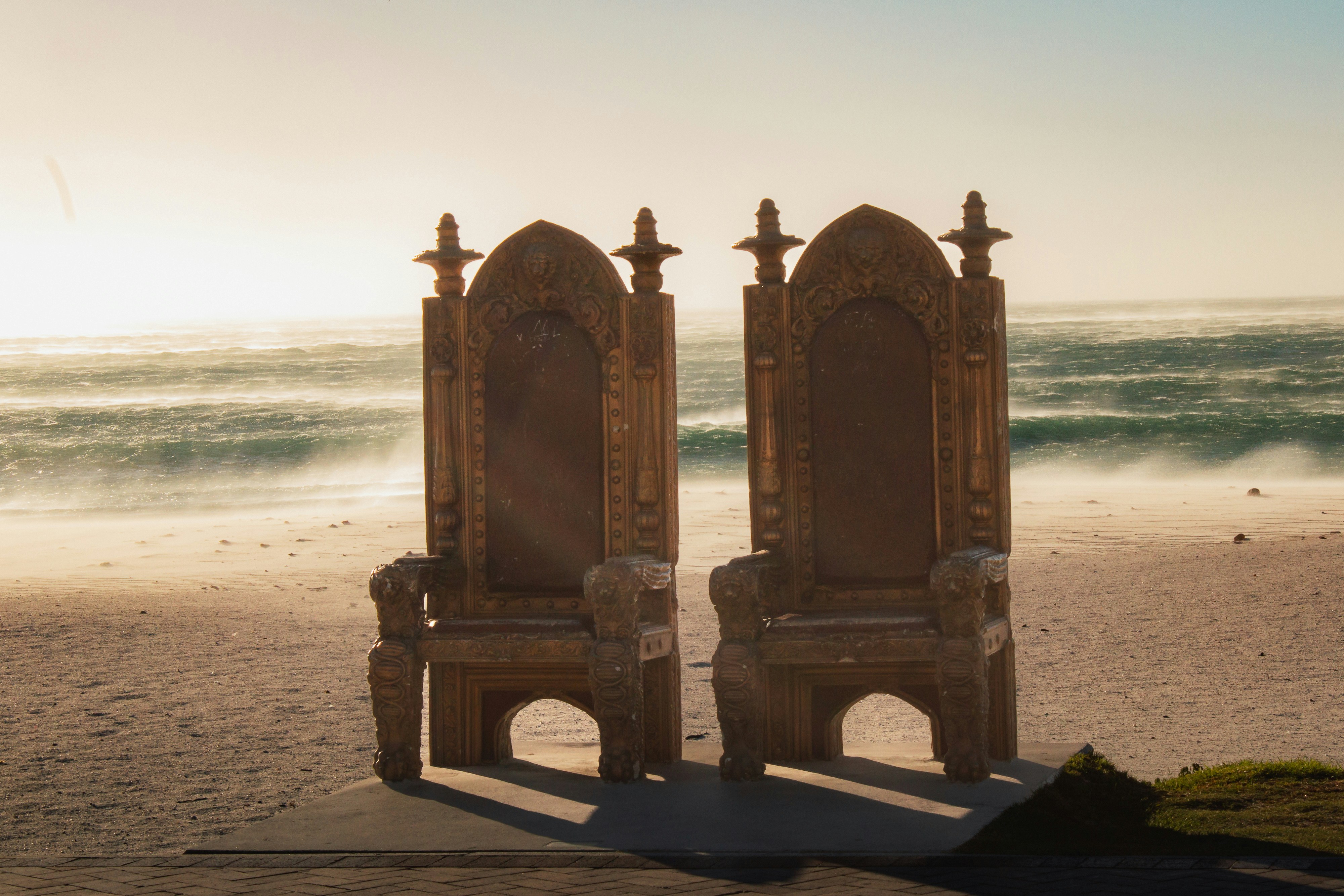 A couple of chairs sitting on top of a sandy beach