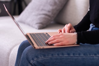 A woman sitting on a couch using a laptop computer