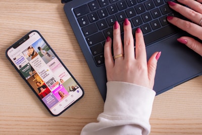A woman typing on a laptop computer next to a cell phone