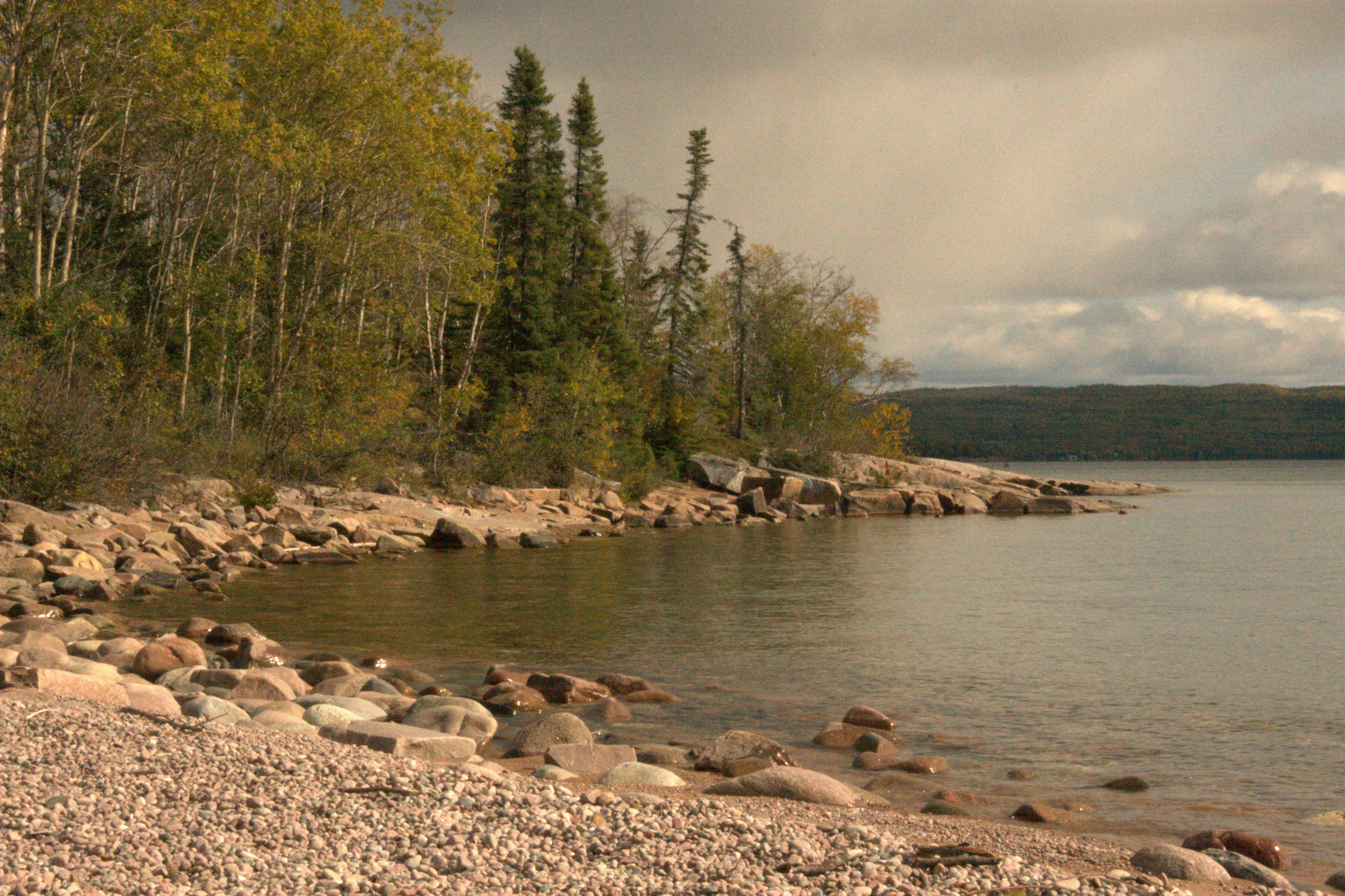 Ein Gewässer, umgeben von Bäumen und Felsen