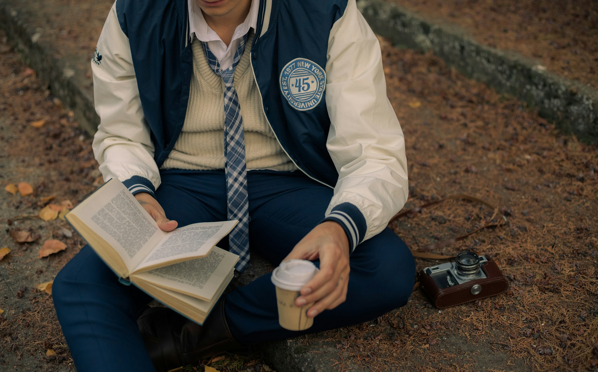 A man sitting on the ground reading a book