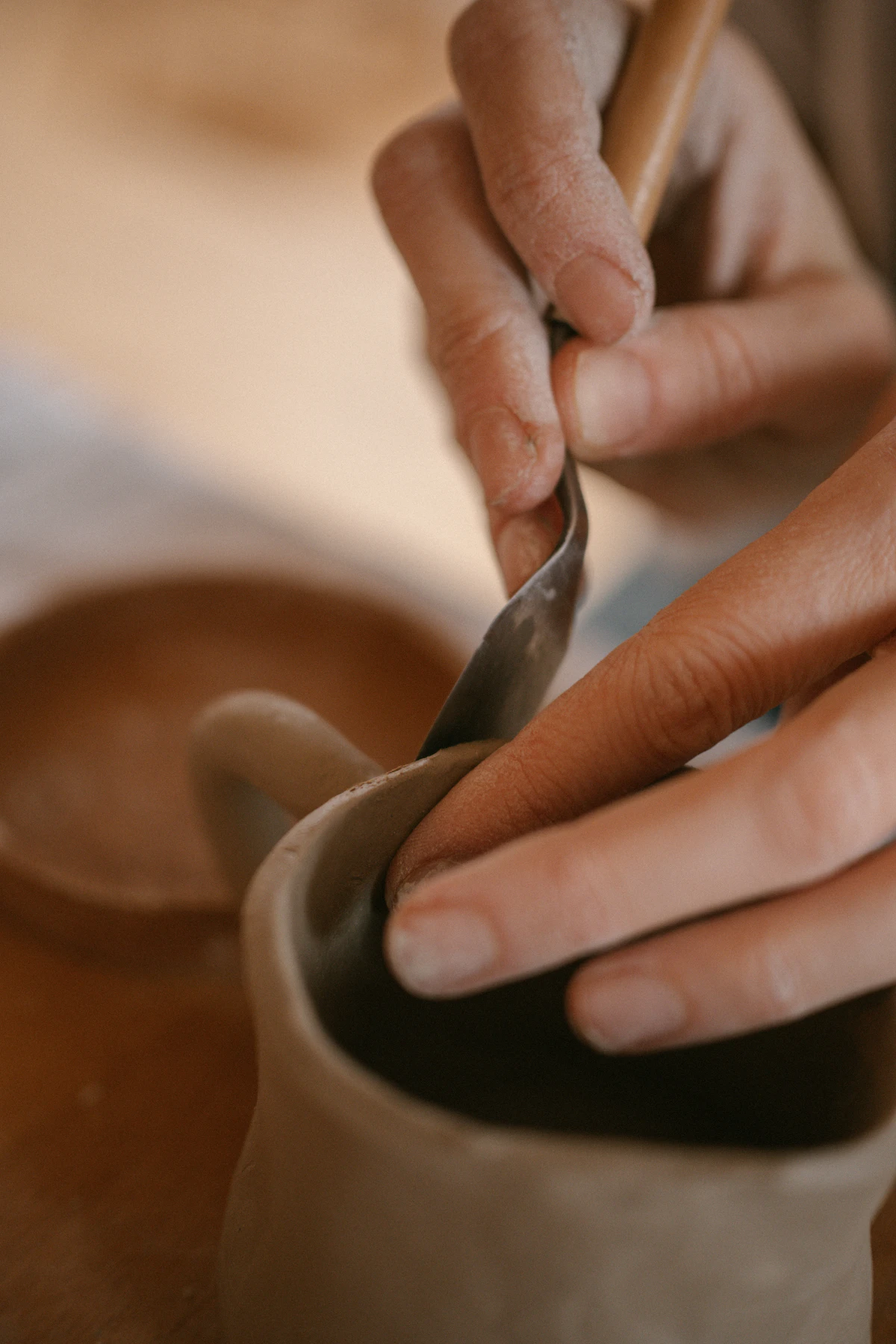 Maker trimming a handmade ceramic piece in a pottery studio while thinking about product costs