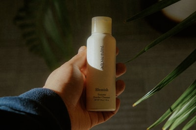 A person holding a bottle of lotion in their hand