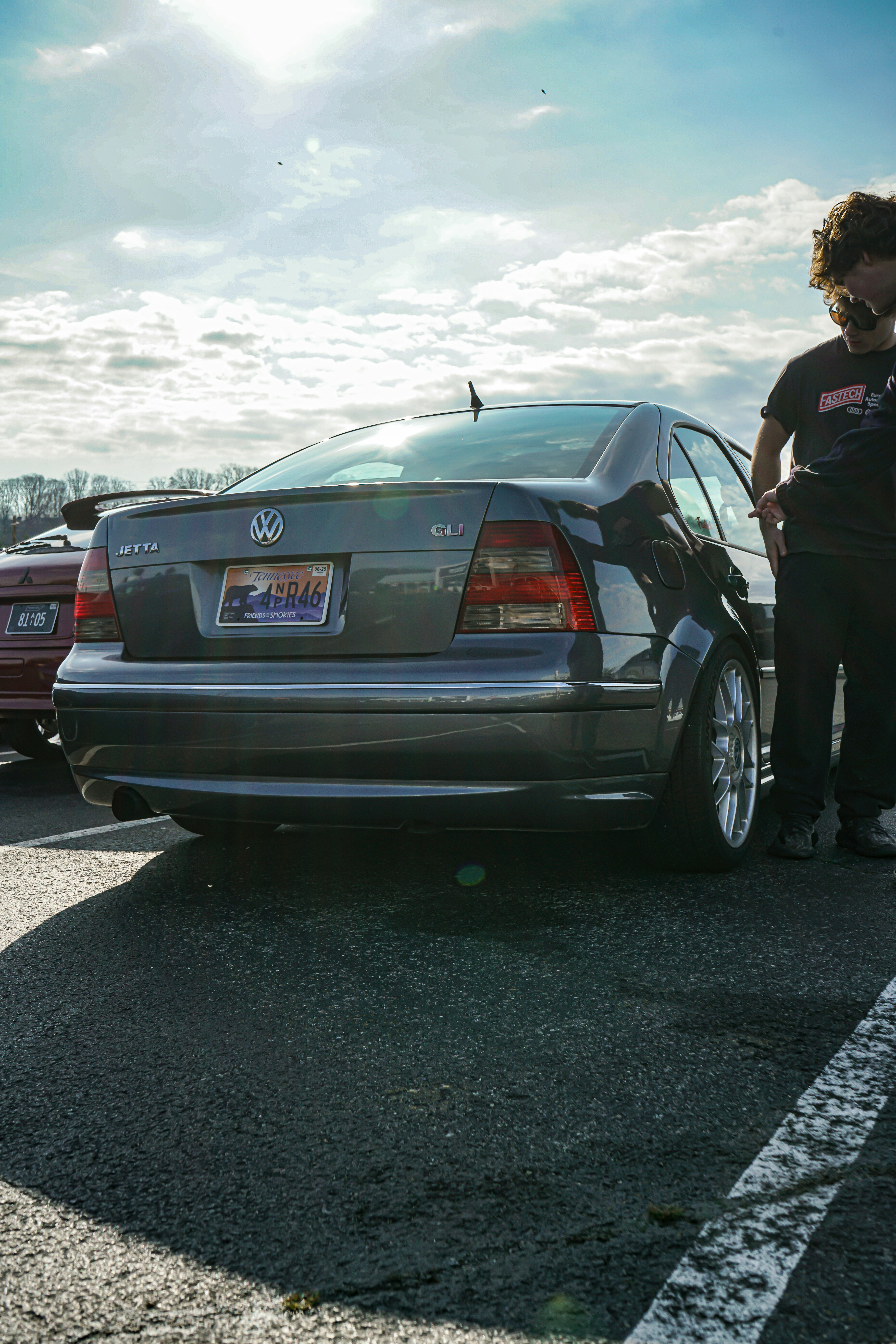 A man standing next to a parked car in a parking lot