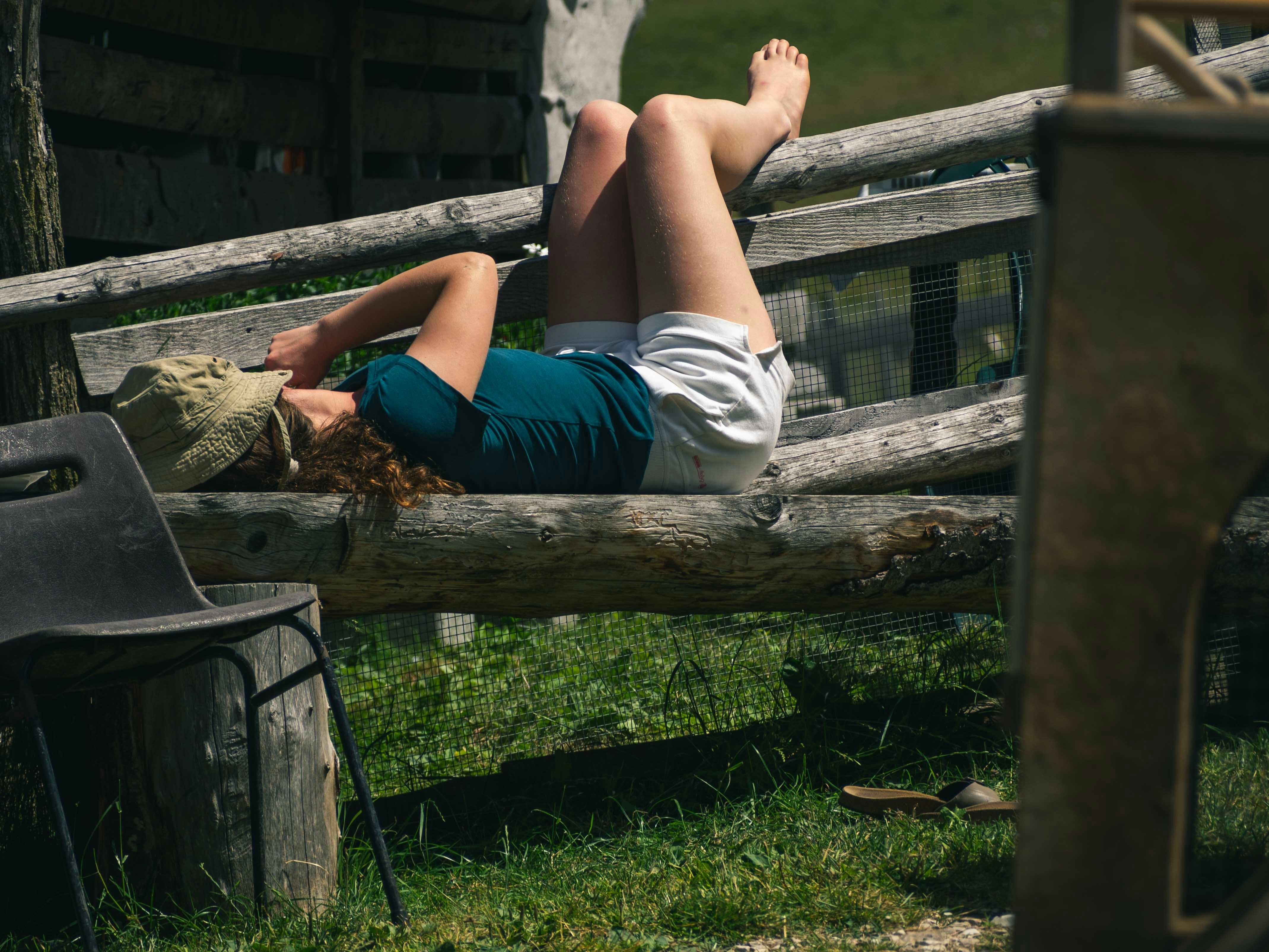 A woman laying on top of a wooden bench
