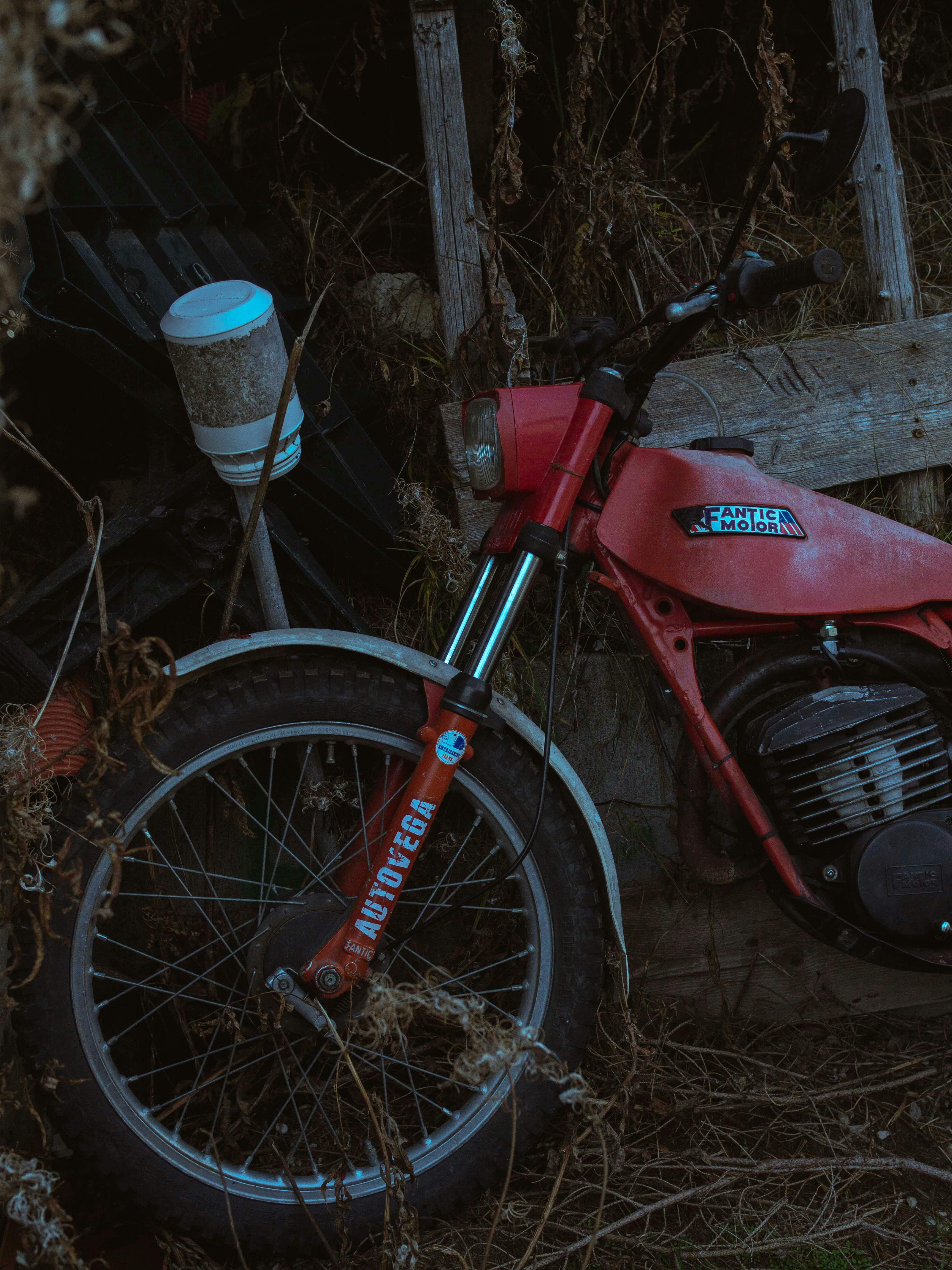 A red motorcycle parked next to a wooden fence