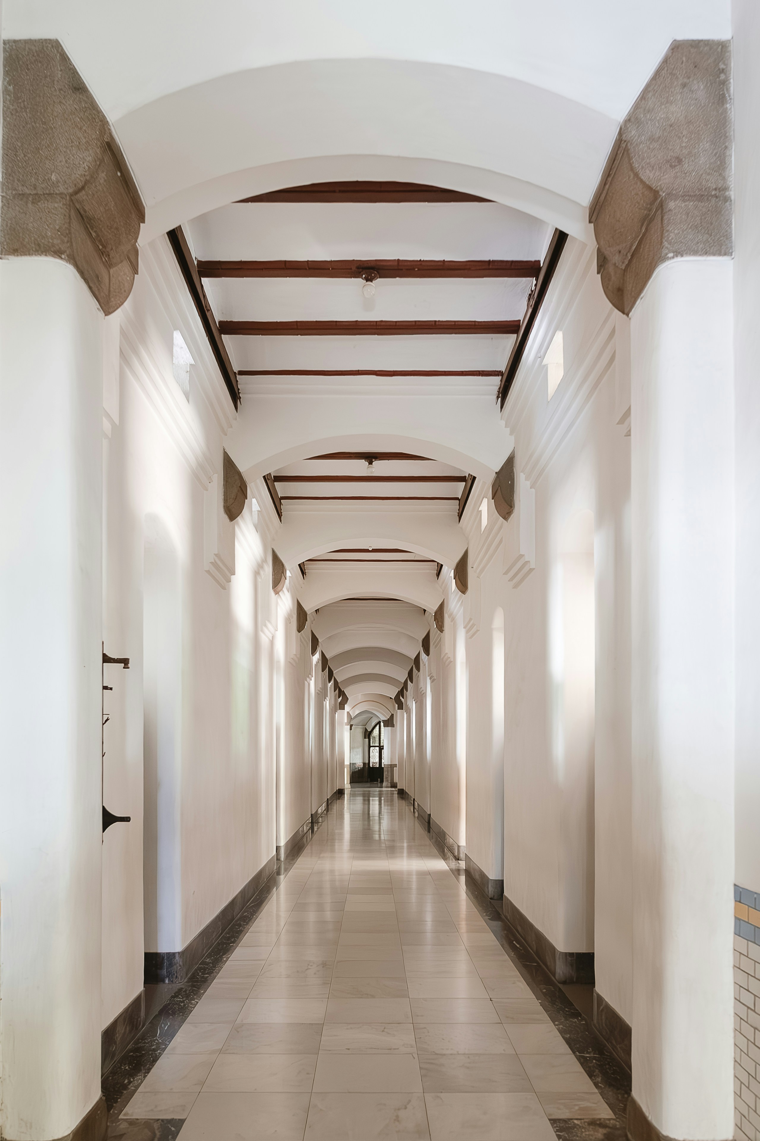 A long hallway with white walls and tiled floors
