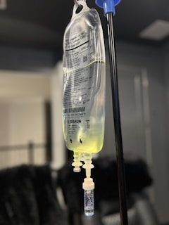 A bottle with a liquid inside of it hanging from a hook