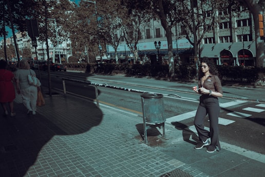 A woman running down a sidewalk next to a trash can