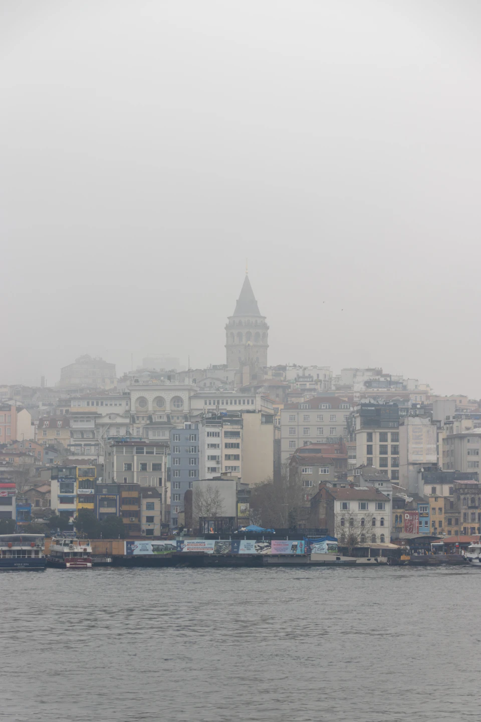 Istanbul skyline at dusk viewed from the Bosphorus, with the silhouettes of historic minarets and the city lights reflecting on the water as autumn weather settles in