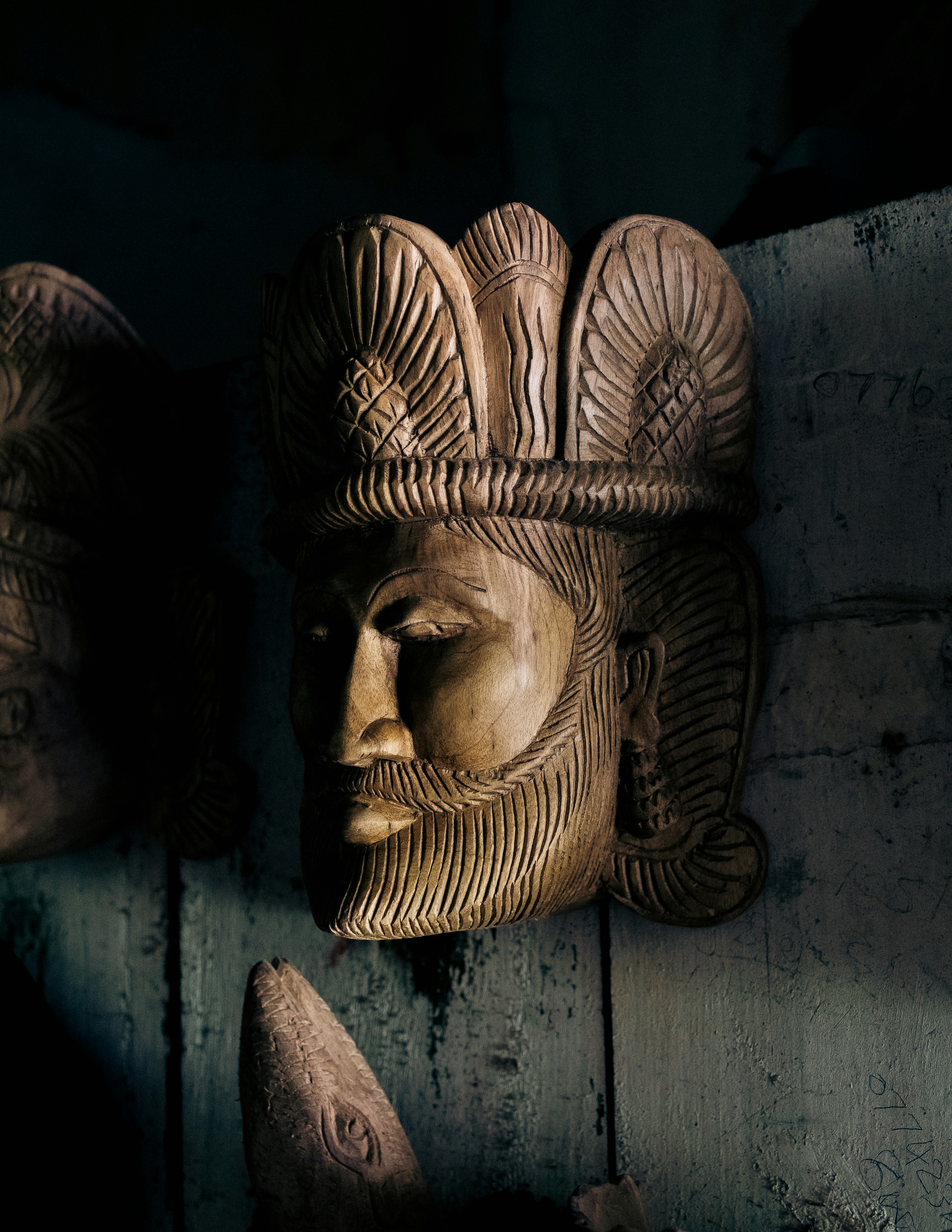 A wooden mask is hanging on a wall